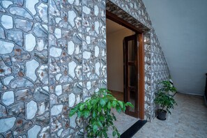A stone wall with a wooden door leading to a room. There are two potted plants in the foreground. - Seraya Stays (Mandrem)