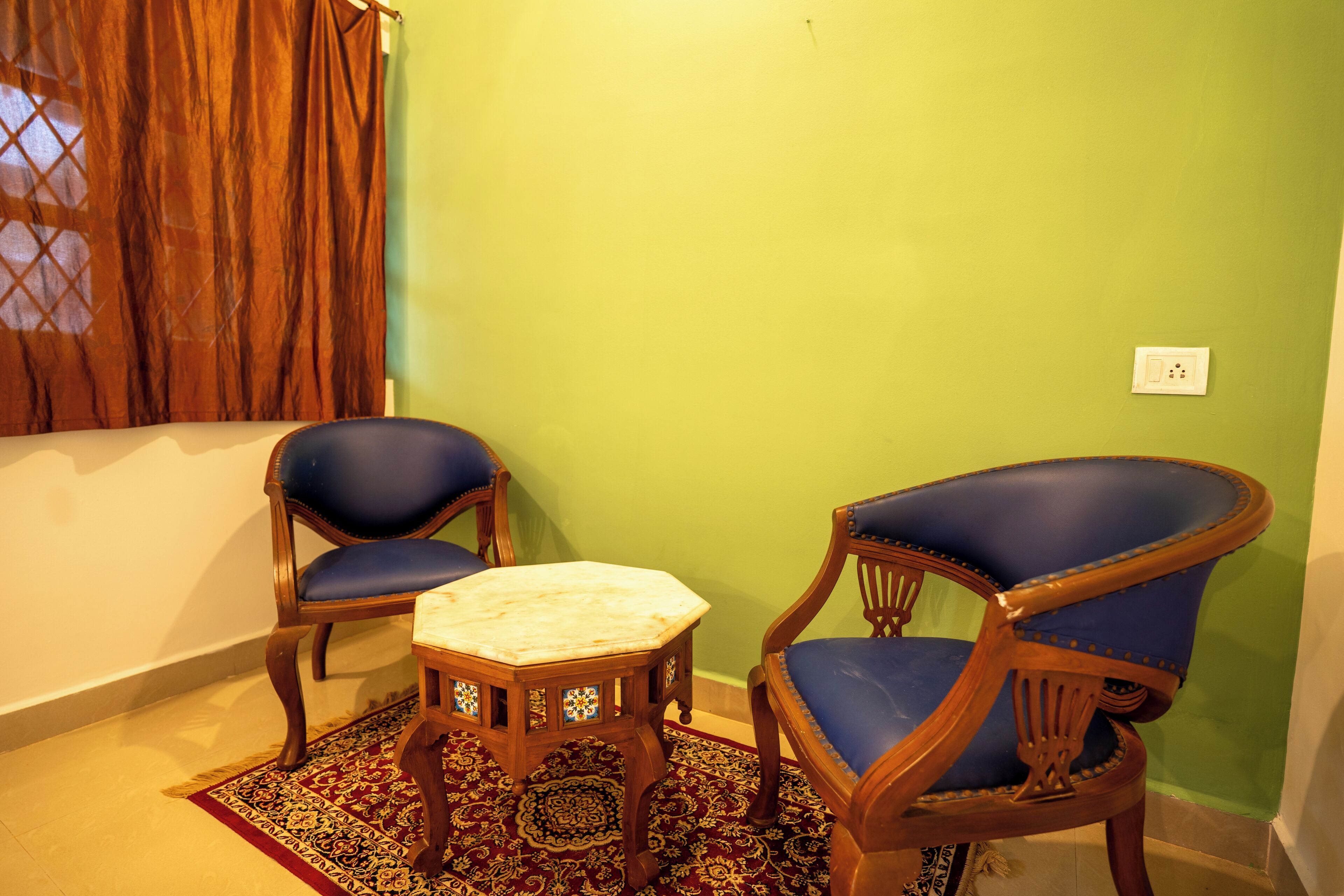 Una habitación con dos sillones tapizados en azul, una mesita de madera y una alfombra estampada.