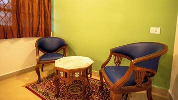 Una habitación con dos sillones tapizados en azul, una mesita de madera y una alfombra estampada.