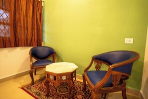 Una habitación con dos sillones tapizados en azul, una mesita de madera y una alfombra estampada.