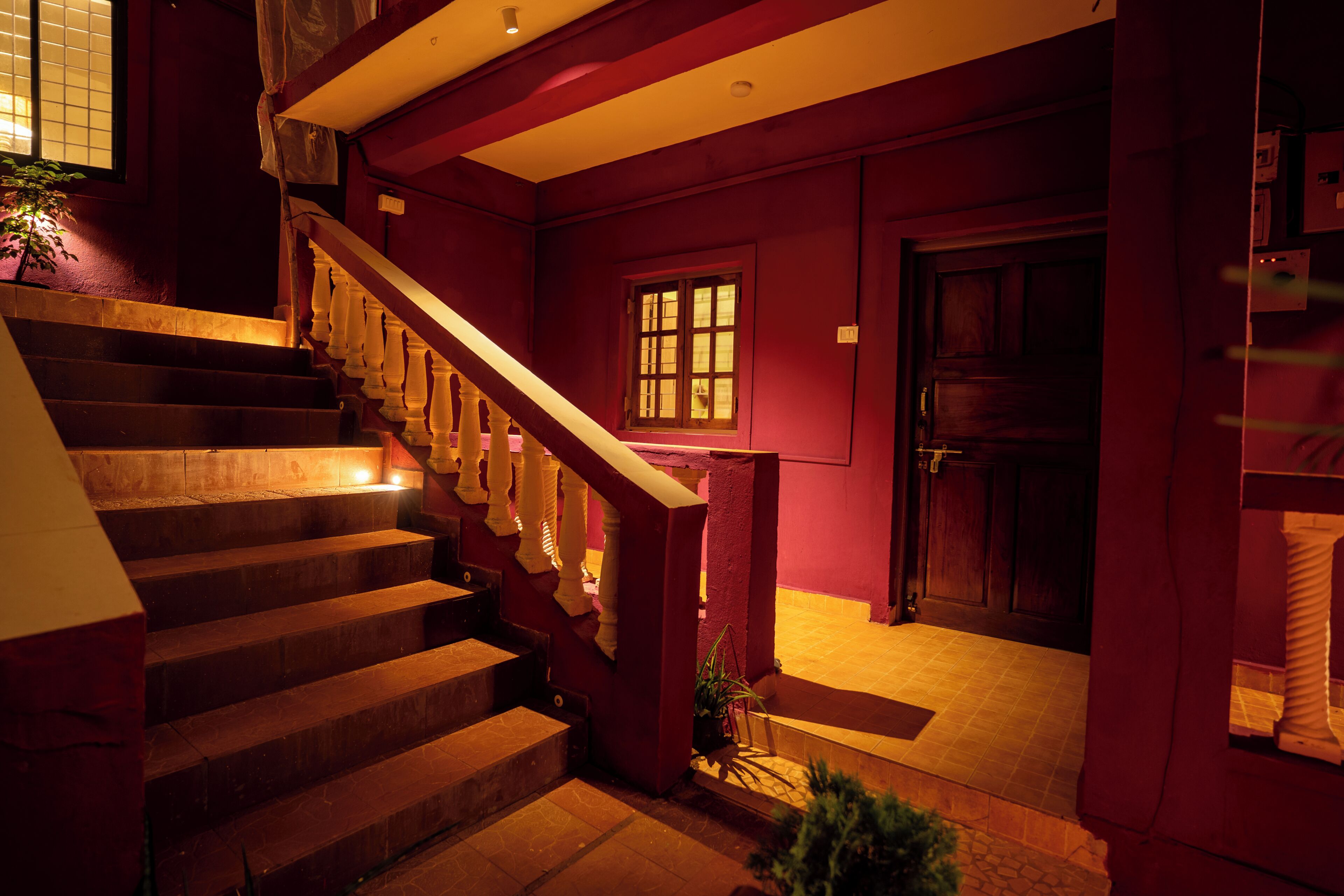 A staircase with wooden steps and white balusters, leading to a landing with a door and a window.