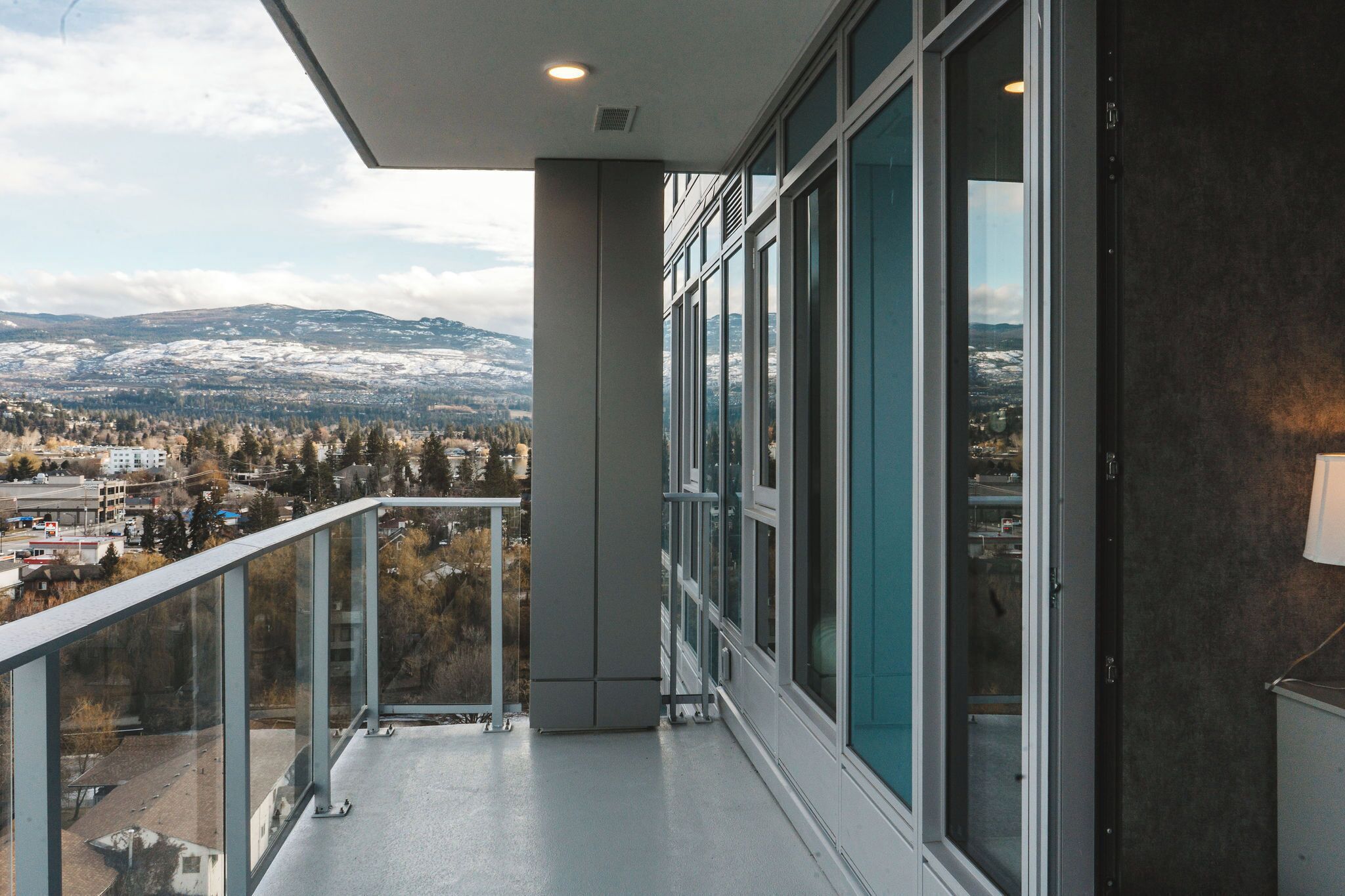 A balcony with a city view, large windows, and a modern architectural design.