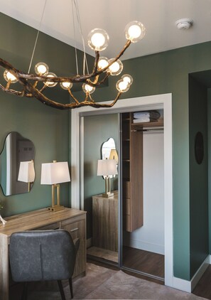 A modern bathroom with a vanity, two lamps, a mirror, and a chandelier. - Luna Suite | Pet-Friendly 1BR (Kelowna)
