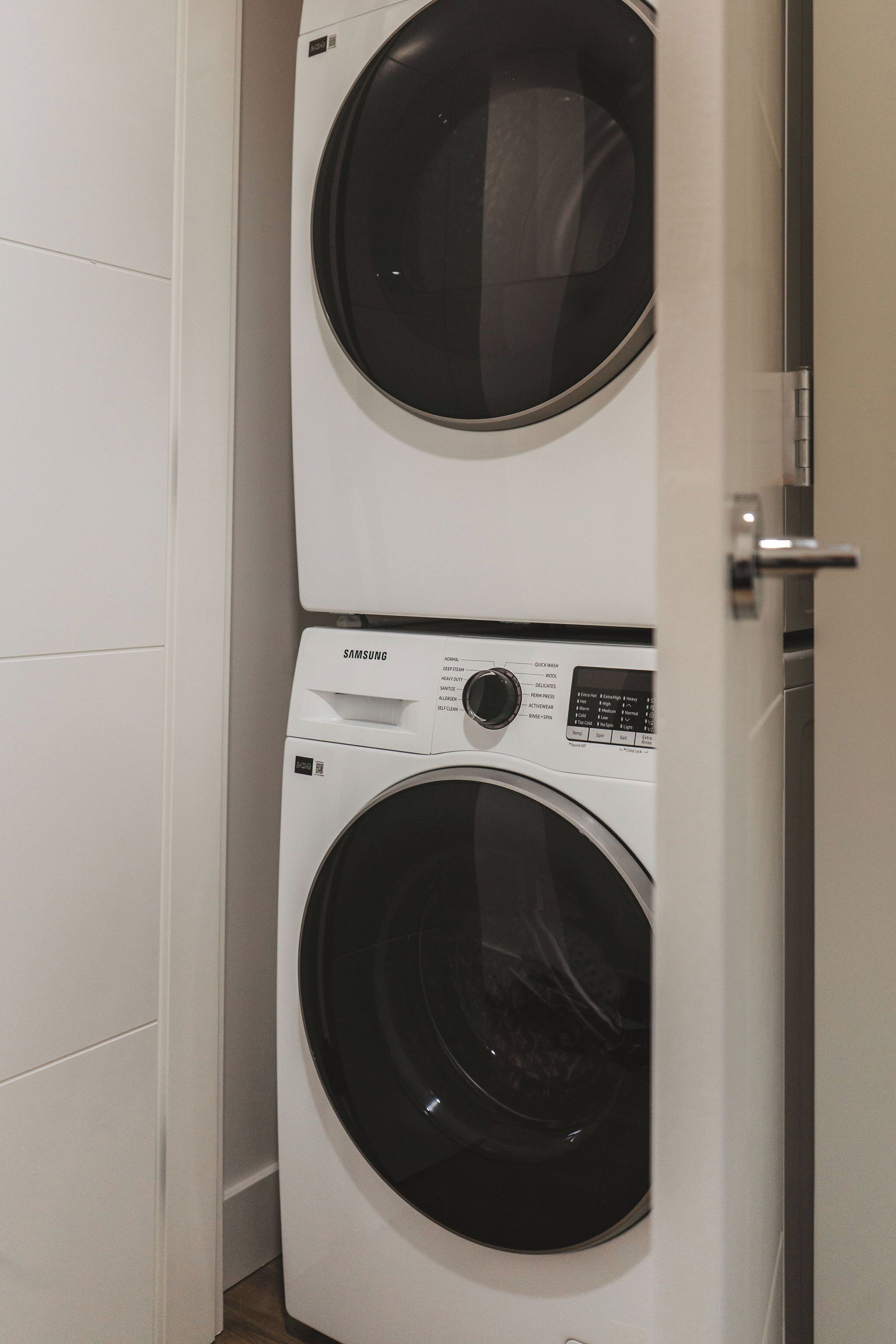 A stacked washer and dryer unit in a corner of a room.