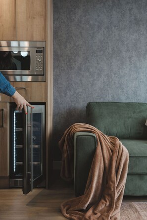 A kitchen with a microwave, a refrigerator, and a person opening the refrigerator door. - Luna Suite | Pet-Friendly 1BR (Kelowna)