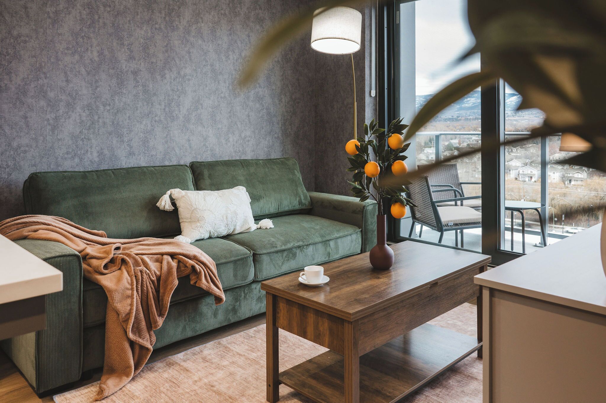 A modern living room with a green sofa, a coffee table, and a view of the outdoors.