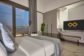 A hotel room with a bed, a desk, a TV, and a balcony with a view. - Stylish Modern Studio | MAG 910, Meydan Community (Dubai)