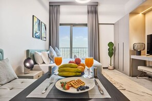 A modern hotel room with a dining area, a bed, a balcony, and a view of the sky. - Stylish Modern Studio | MAG 910, Meydan Community (Dubai)