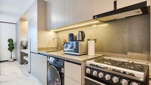 A modern kitchen with a built-in dishwasher, a gas stove, and a coffee maker. - Stylish Modern Studio | MAG 910, Meydan Community (Dubai)