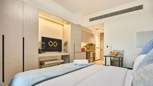 A hotel room with a bed, a desk, a kitchenette, and a bathroom. - Stylish Modern Studio | MAG 910, Meydan Community (Dubai)