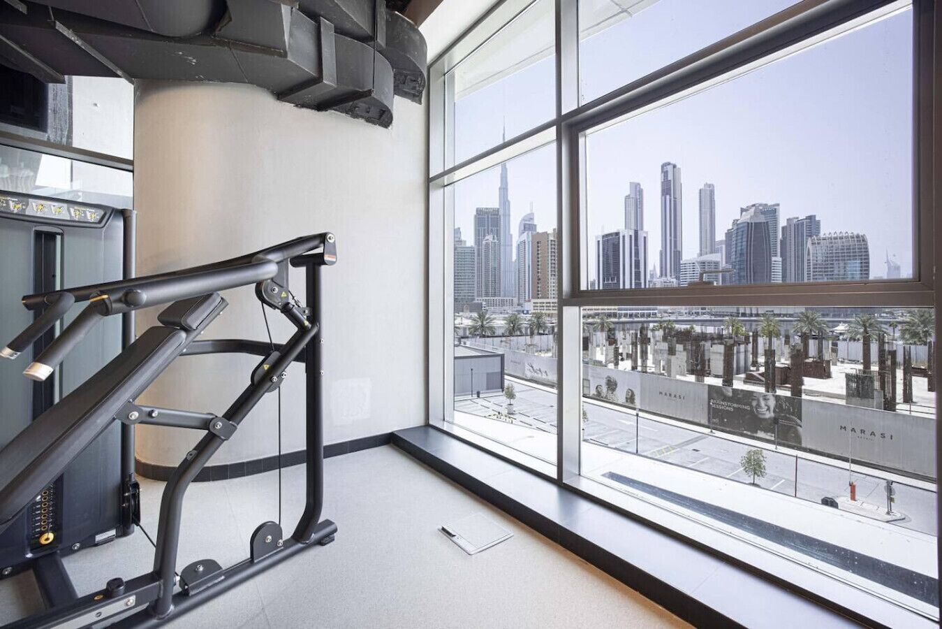 Un gimnasio con equipo de ejercicio y un amplio ventanal con vistas al horizonte urbano.