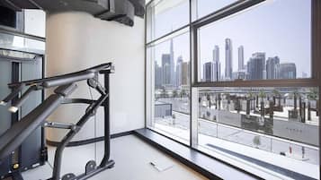 A gym with exercise equipment and a large window offering a city skyline view.