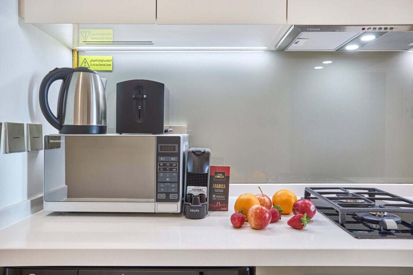 A modern kitchen with a microwave, coffee maker, and a gas stove.