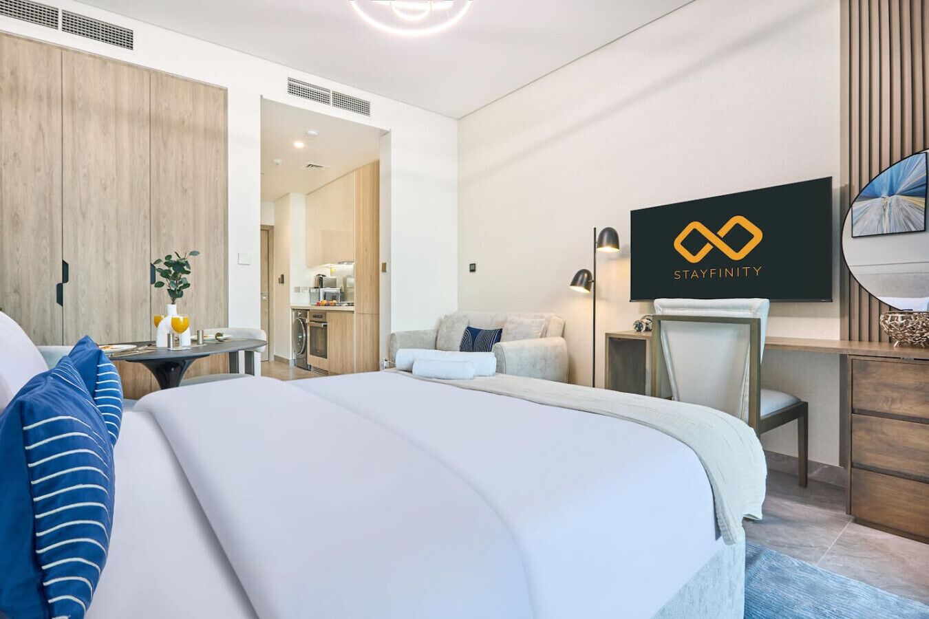 Una habitación de hotel moderna con una cama, un escritorio, una silla y una kitchenette al fondo.