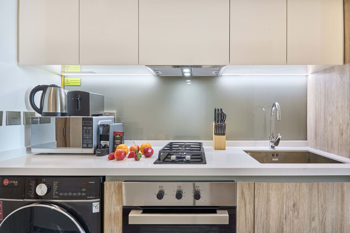 Una cocina moderna con lavavajillas integrado, cafetera, cocina a gas y un lavabo con grifo.