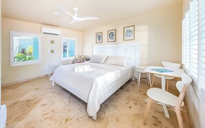Ein Schlafzimmer mit Bett, Nachttisch, Sessel und Deckenventilator.