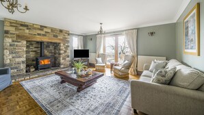 Ein gemütliches Wohnzimmer mit Kamin aus Stein, bequemen Sitzgelegenheiten und einem Fernseher.