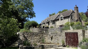 Ein Steinhhaus mit mehreren Schornsteinen, einer Steinmauer und einer Holztür.