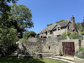 Ein Steinhhaus mit mehreren Schornsteinen, einer Steinmauer und einer Holztür.