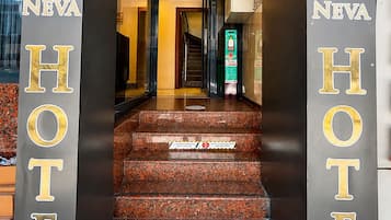 Entrada de un hotel con una escalera que conduce al interior, un mostrador de recepción y un letrero que indica la habitación número 21.