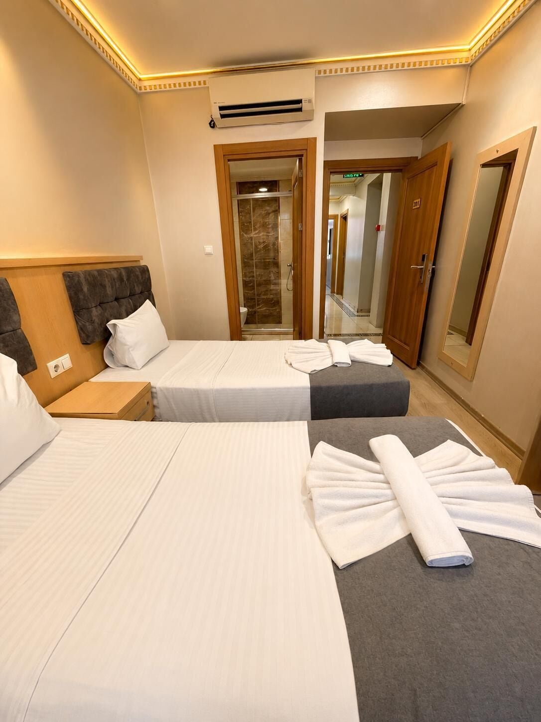 Habitación de hotel con dos camas, ducha y espejo.
