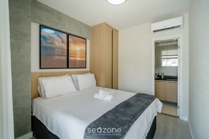 A modern hotel room with a neatly made bed, a painting of a sunset, and a view into the kitchen area. - Contemporary Apartment 400 m From the sea Blb0507 (Salvador)