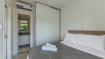 A modern hotel room with a bed, a bathroom, and a kitchenette.