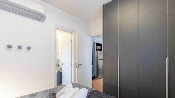 Un dormitorio moderno con una cama grande, un armario y una kitchenette al fondo.