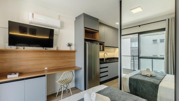Una cucina moderna con TV integrata, frigorifero e zona pranzo con piano in legno.