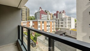 Un balcone con vista sulla città, che mostra edifici a più piani e auto parcheggiate.