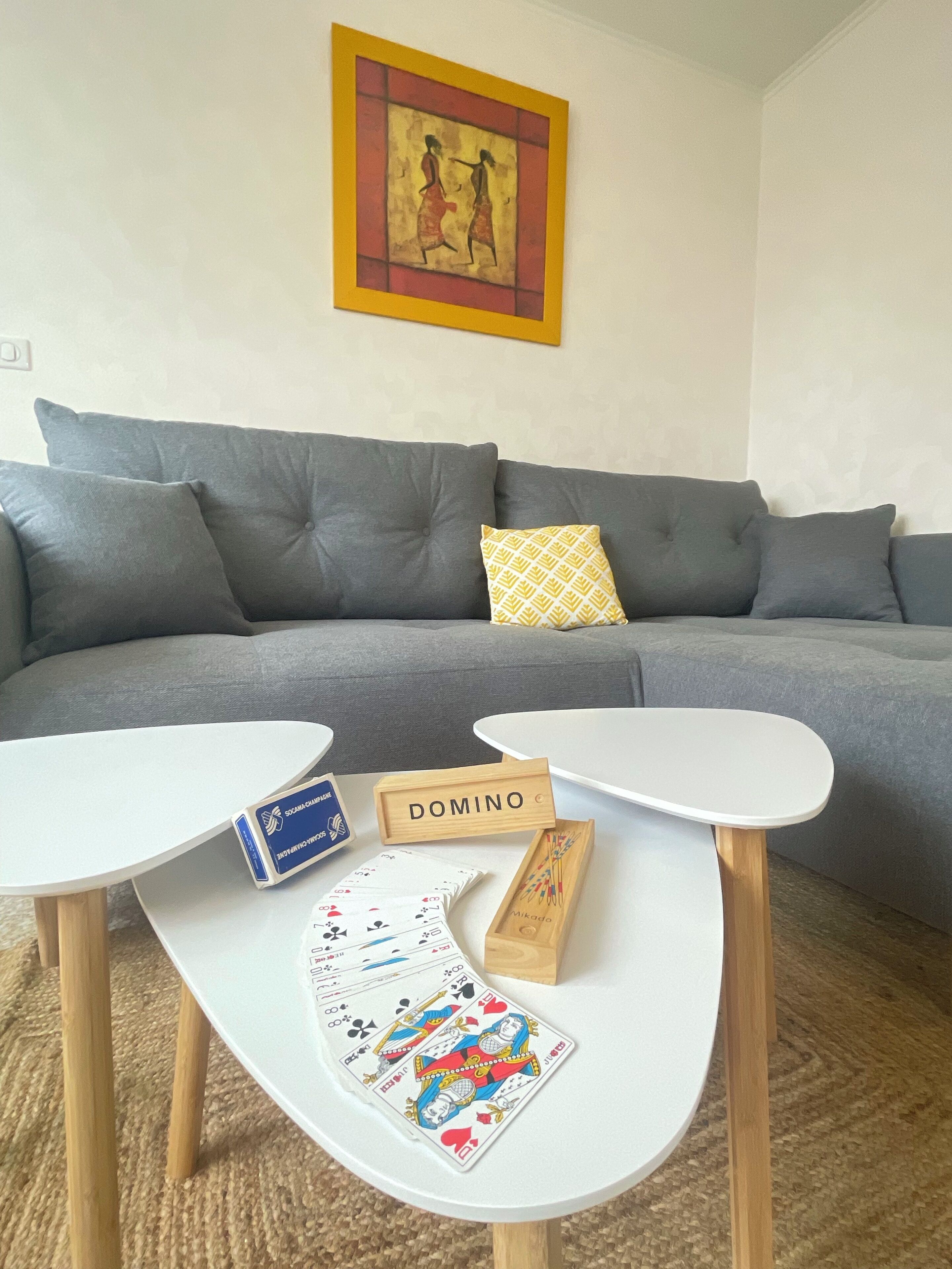 A living room with a grey sofa, a white coffee table, and a painting on the wall.