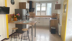 A compact kitchen with a dining area, a refrigerator, a sink, and a window with blinds.