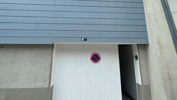 A building with a garage door, a window, and a door with a no parking sign.