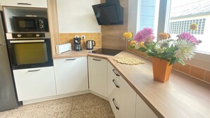 A kitchen with a microwave, coffee maker, and a potted plant with flowers.