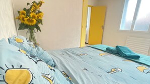A bedroom with a bed, a vase with sunflowers, and a window.