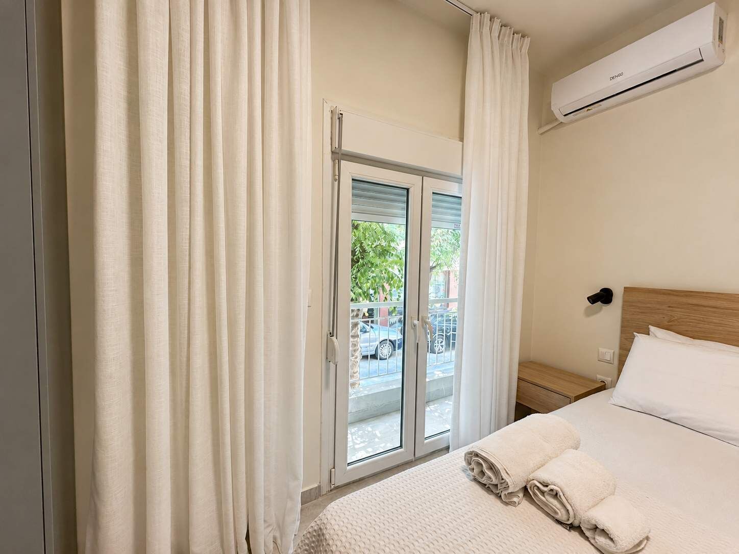 Ein Hotelzimmer mit Bett, einem fenster mit Vorhängen, einer Klimaanlage und Blick nach draußen.