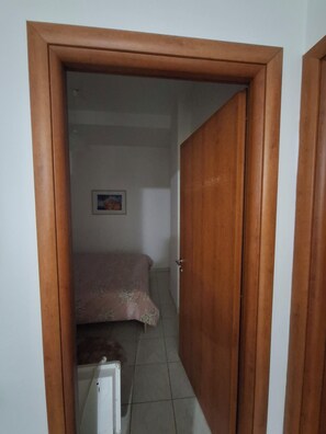 Ein Zimmer mit einem Bett, einem Heizkörper und einer Tür zu einem anderen Raum.