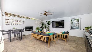 A modern living room with a fireplace, seating area, and a ceiling fan. - Sandy Toes – Three Lux Retreats with Heated Pool (Nelson Bay)