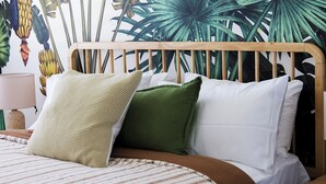 A bed with a wooden headboard, striped bedding, and two pillows. - Sandy Toes – Lux Retreat with Heated Pool (Nelson Bay)