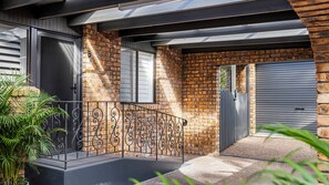 A residential building with a brick facade, a metal gate, and a gated driveway. - Sandy Toes Hideaway – Lux Pet-Friendly Retreat (Nelson Bay)