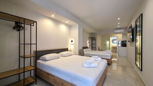 Ein modernes Hotelzimmer mit zwei Betten, einem Holzkopfteil, einer eingebauten Garderobe und einem durch eine geöffnete Tür einsehbaren Badezimmer.