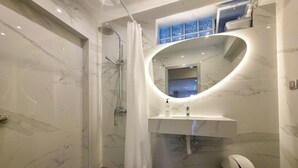 Ein modernes Badezimmer mit Dusche, Waschbecken und Spiegel.