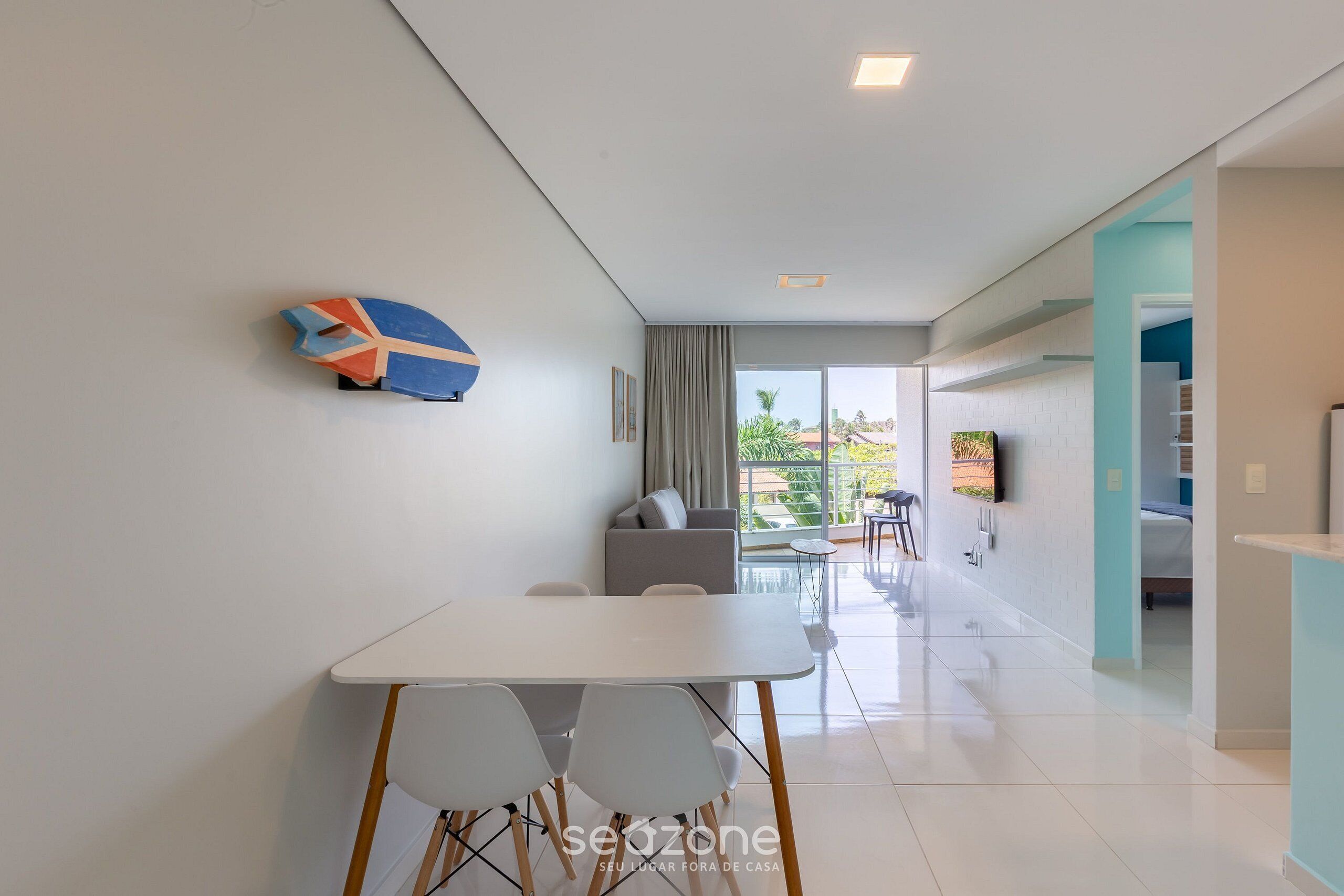 A modern living room with a white table and chairs, a grey sofa, and a colorful wall decoration.