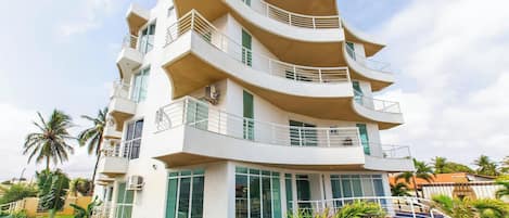 A multi-story hotel with balconies, a swimming pool, and a tropical garden.