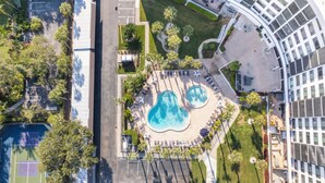 An aerial view of a resort with a central pool area, lounge chairs, and a tennis court. - 2BD Condo with Pool and Patio Ground Floor (Siesta Key)