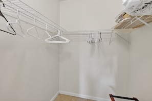 A corner of a room with a white wall, a metal shelf unit, and a wooden floor. - 2BD Condo with Pool and Patio Ground Floor (Siesta Key)