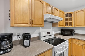 A kitchen with wooden cabinets, a coffee maker, a microwave, and an oven. - 2BD Condo with Pool and Patio Ground Floor (Siesta Key)
