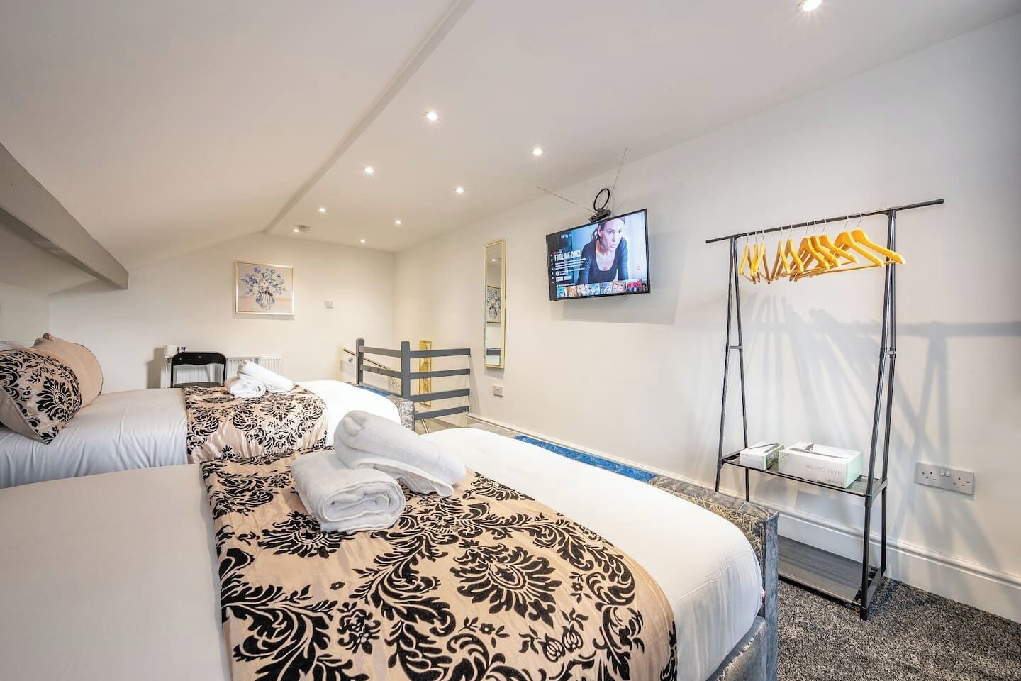 Une chambre d’hôtel avec deux lits, une télévision, une armoire et une petite table.