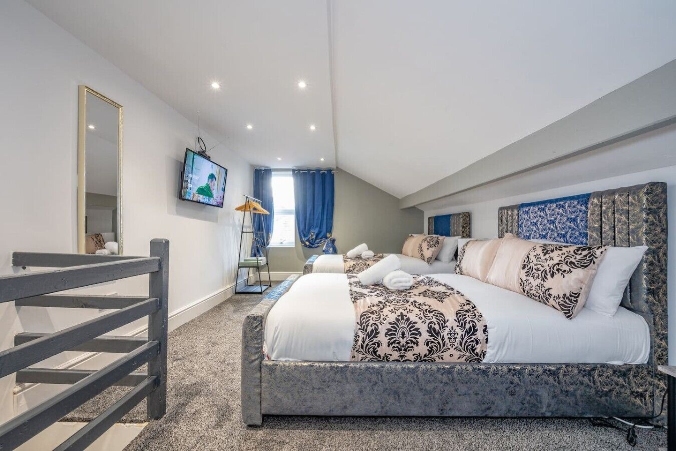 Habitación de hotel con una cama grande, televisión, espejo y vistas al exterior.