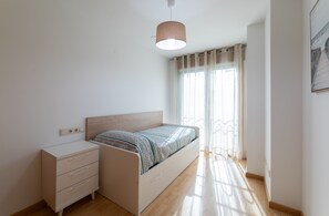 A bedroom with a bed, bedside table, and a window with curtains. - Baleo Valdoviño Apartment (Valdoviño)
